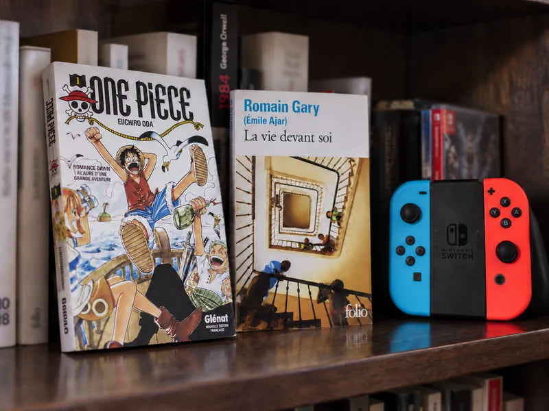 Romans, manga et manette Nintendo Switch réunis sur une étagère.